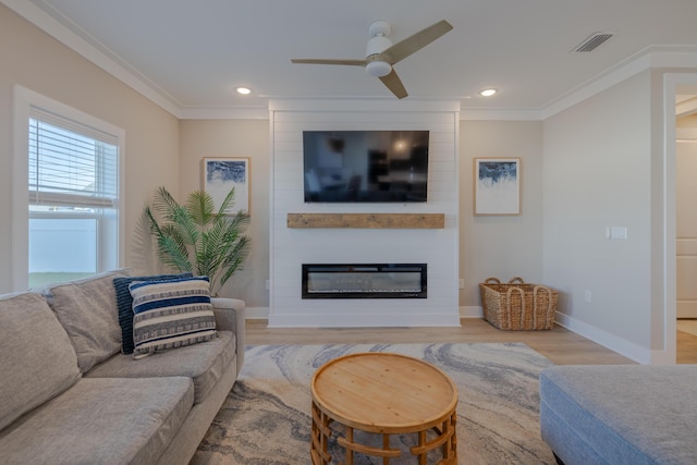 living area featuring ceiling fan, visible vents, a fireplace, and crown molding