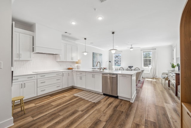 kitchen featuring a peninsula, stainless steel dishwasher, white cabinets, a ceiling fan, and a sink