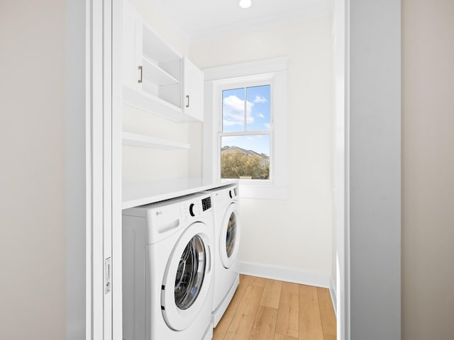 375 Morgans Trl, Santa Rosa Beach, FL 32459 - clothes washing area with crown molding, baseboards, light wood-type flooring, cabinet space, and washer and clothes dryer