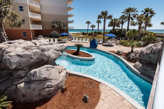 pool with a patio and a water view