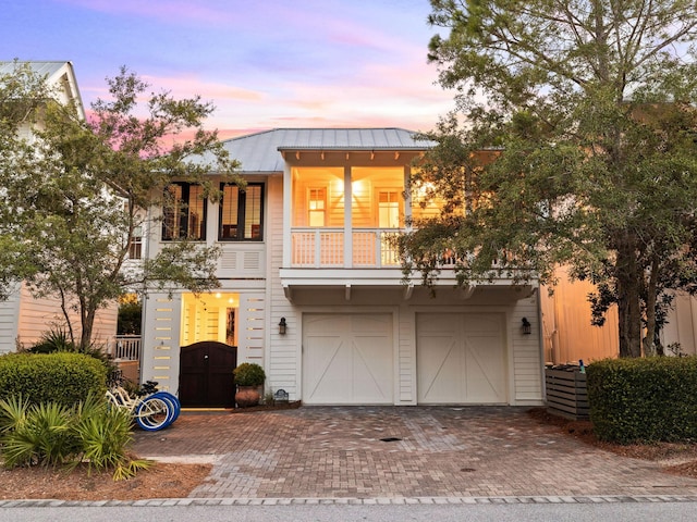 223 Western Lake Dr, Santa Rosa Beach, FL 32459 - view of front of home featuring a standing seam roof, an attached garage, a balcony, metal roof, and decorative driveway