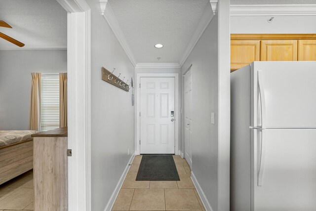 doorway to outside featuring light tile patterned floors, baseboards, ceiling fan, a textured ceiling, and crown molding