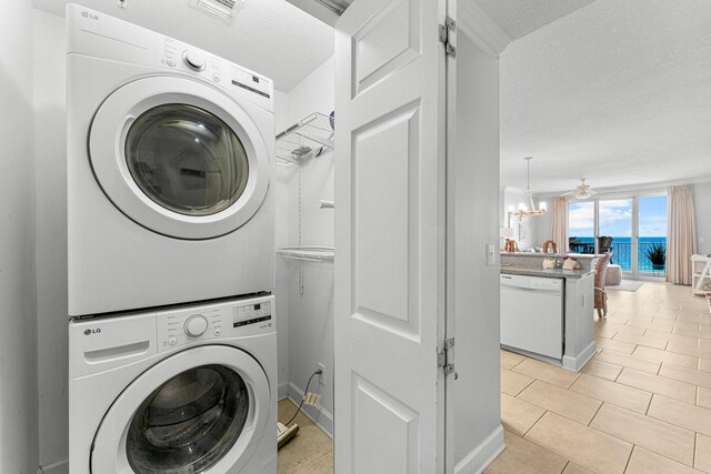 laundry room with visible vents, laundry area, light tile patterned flooring, stacked washer / drying machine, and a textured ceiling