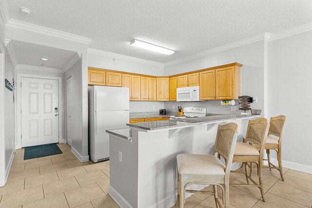 kitchen with a breakfast bar area, ornamental molding, light stone counters, a peninsula, and white appliances