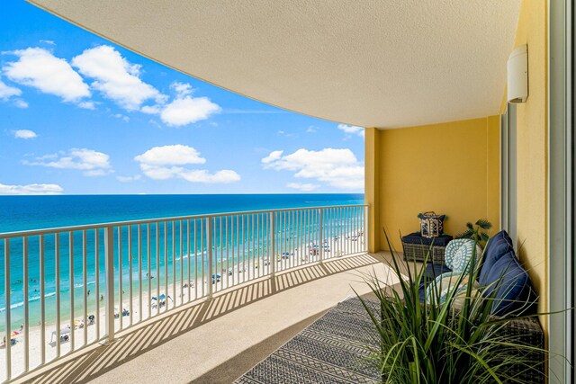 balcony featuring a view of the beach and a water view