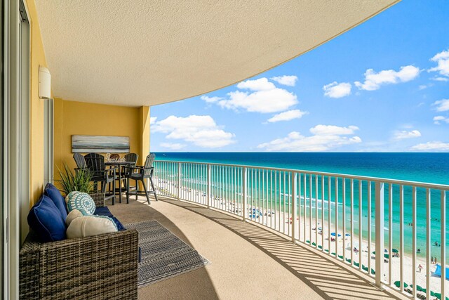 balcony featuring a view of the beach and a water view