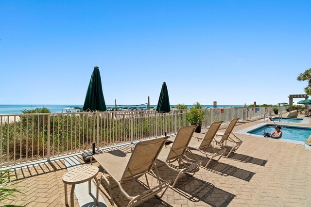 view of patio with a community pool, a water view, and fence