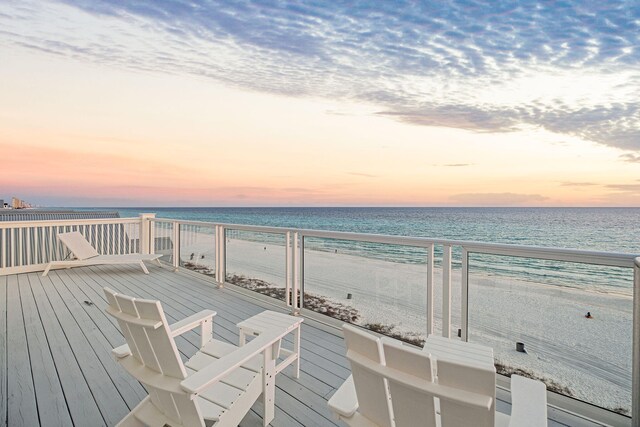 deck at dusk with a view of the beach and a water view