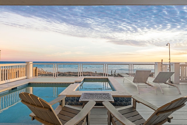 view of swimming pool with a pool with connected hot tub, a beach view, and a water view