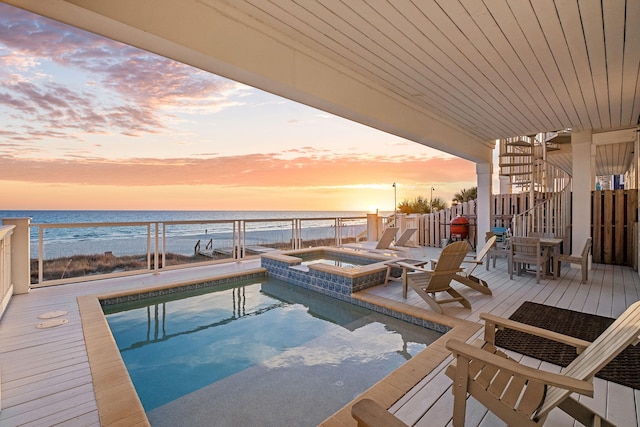 view of swimming pool featuring an in ground hot tub, a deck with water view, a view of the beach, and a fenced in pool