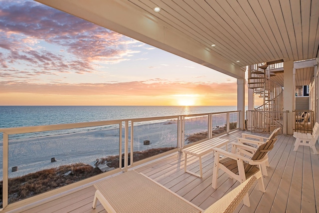 deck featuring a beach view, stairway, and a water view
