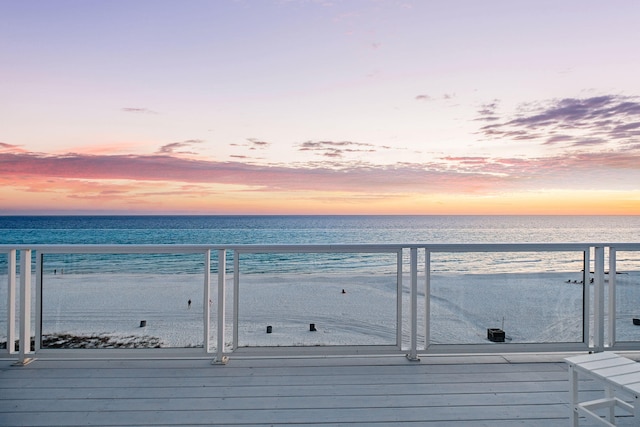 wooden terrace featuring a beach view and a water view