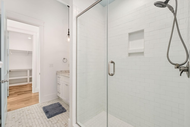 bathroom with tile patterned floors, a walk in closet, vanity, and a shower stall
