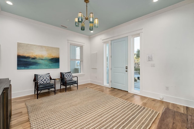 foyer with visible vents, wood finished floors, an inviting chandelier, crown molding, and baseboards