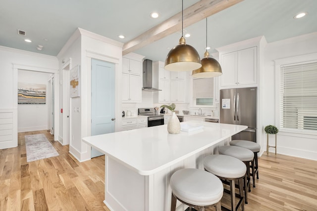 kitchen featuring a kitchen breakfast bar, wall chimney range hood, a kitchen island, and stainless steel appliances