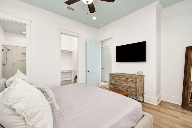 bedroom featuring baseboards, visible vents, ornamental molding, a walk in closet, and light wood-type flooring