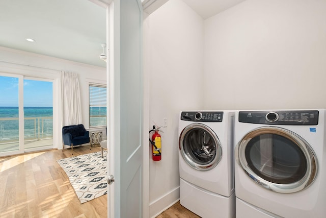 laundry area featuring baseboards, wood finished floors, washing machine and dryer, and laundry area