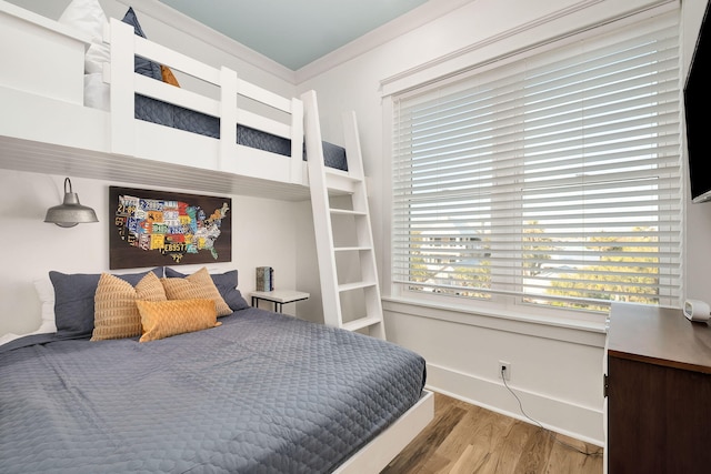 bedroom with baseboards, wood finished floors, and ornamental molding