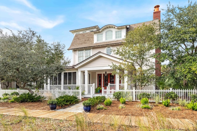 view of front of home with covered porch, a chimney, a fenced front yard, and a sunroom