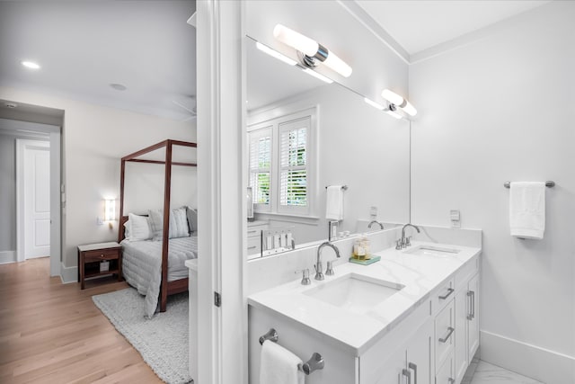 ensuite bathroom with baseboards, double vanity, connected bathroom, and a sink