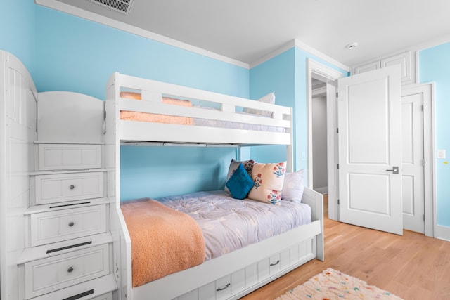 bedroom with crown molding, light wood-style floors, and visible vents