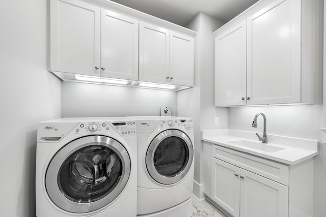clothes washing area featuring marble finish floor, washing machine and clothes dryer, cabinet space, and a sink