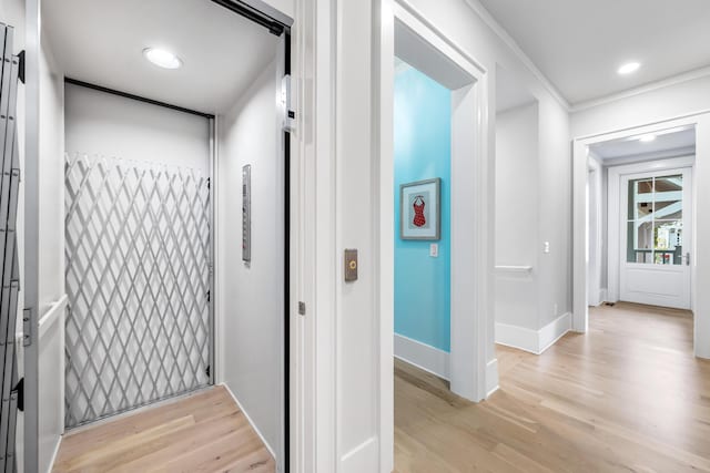 hallway with elevator, recessed lighting, light wood-style flooring, and baseboards