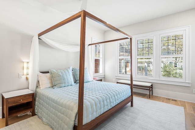 bedroom with baseboards, visible vents, and wood finished floors