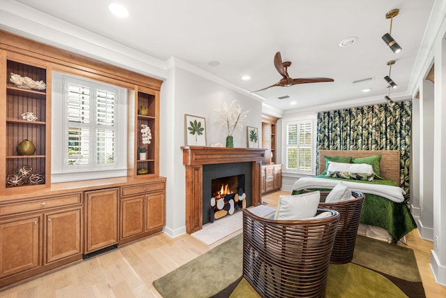 bedroom with light wood-style flooring, visible vents, ornamental molding, recessed lighting, and a lit fireplace