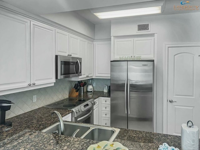kitchen with visible vents, a sink, white cabinetry, stainless steel appliances, and decorative backsplash