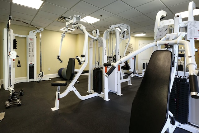 workout area featuring a paneled ceiling and baseboards