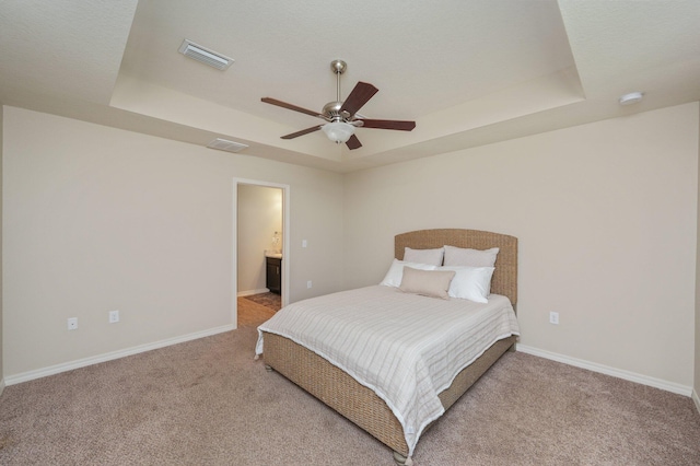 3362 Peeble Dr, Crestview, FL 32539 - carpeted bedroom featuring a raised ceiling, baseboards, ceiling fan, and connected bathroom