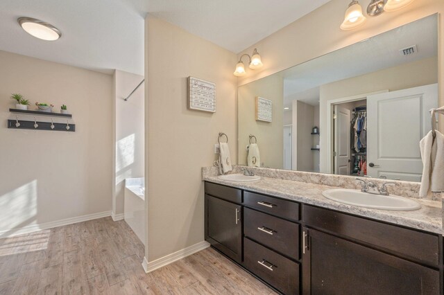 3362 Peeble Dr, Crestview, FL 32539 - bathroom featuring wood finished floors, double vanity, a walk in closet, and baseboards