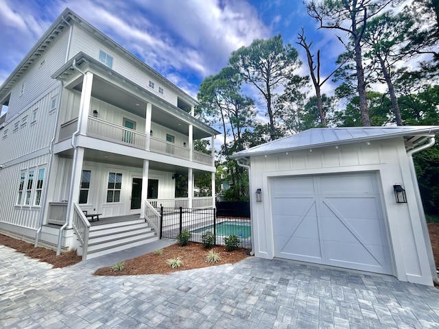 90 Montigo Ave, Santa Rosa Beach, FL 32459 - view of front of house with a balcony, board and batten siding, fence, covered porch, and an outbuilding