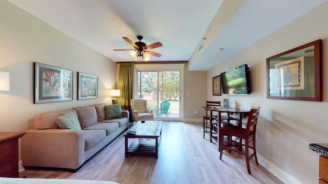 living room with light wood-style flooring, a ceiling fan, visible vents, and baseboards