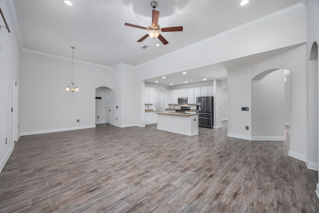 367 Brighton Cv, Freeport, FL 32439 - unfurnished living room with crown molding, ceiling fan with notable chandelier, baseboards, arched walkways, and wood finished floors