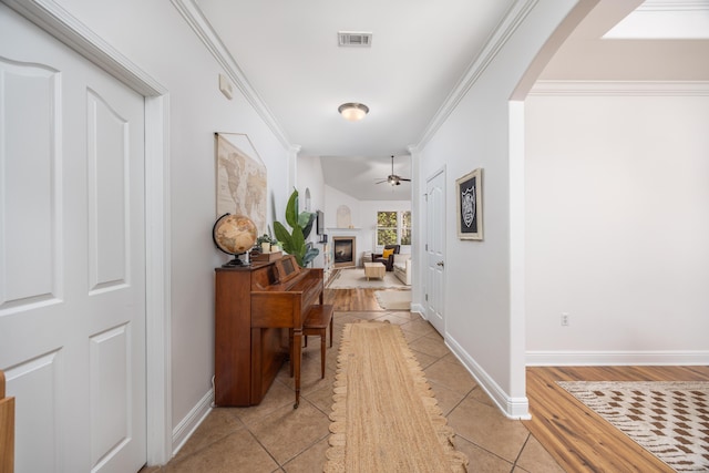 hall featuring visible vents, arched walkways, ornamental molding, and light tile patterned floors