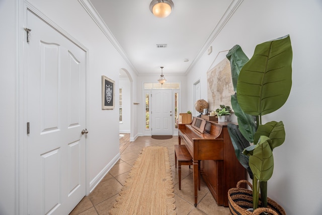 hall featuring light tile patterned flooring, visible vents, baseboards, ornamental molding, and arched walkways