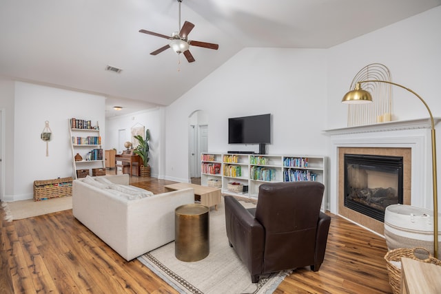 living area featuring a fireplace, wood finished floors, baseboards, visible vents, and ceiling fan