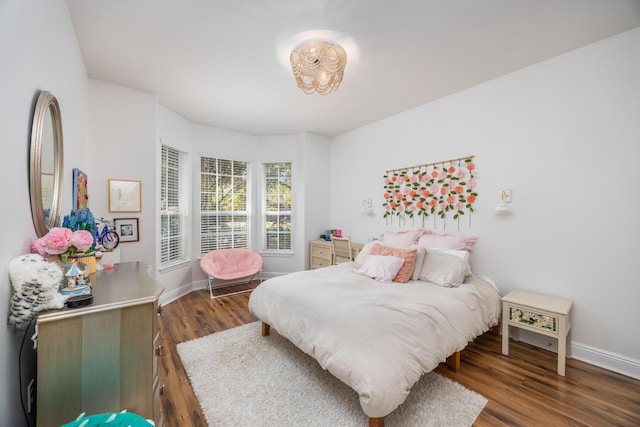 bedroom featuring baseboards, wood finished floors, and a notable chandelier