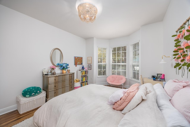 bedroom featuring baseboards, wood finished floors, and a chandelier