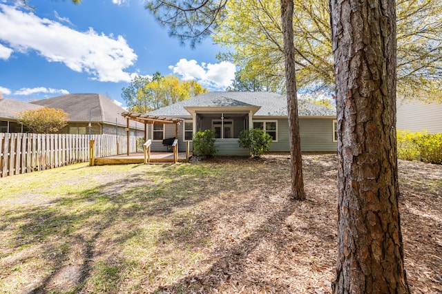 back of house with a sunroom, roof with shingles, fence, a pergola, and a yard
