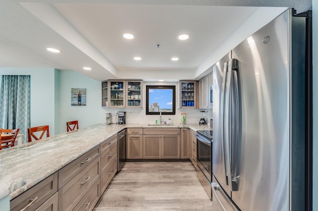 6201 Thomas Dr Unit 1510, Panama City Beach, FL 32408 - kitchen with a sink, a peninsula, glass insert cabinets, light wood-style flooring, and stainless steel appliances