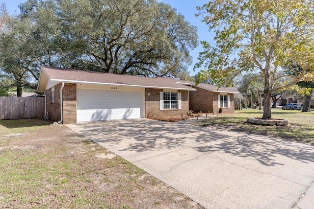 ranch-style home featuring fence, an attached garage, concrete driveway, a front lawn, and brick siding