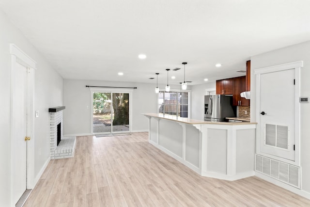 kitchen featuring light wood-style flooring, stainless steel fridge with ice dispenser, and visible vents