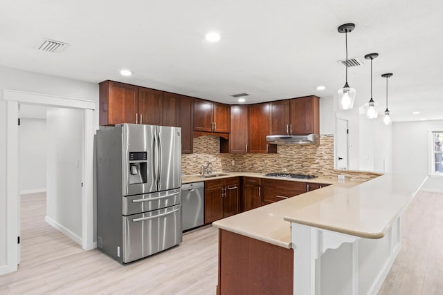 kitchen with visible vents, light countertops, appliances with stainless steel finishes, a peninsula, and a sink
