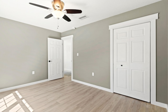 unfurnished bedroom featuring visible vents, baseboards, light wood-style floors, and a closet