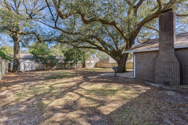 view of yard with an outdoor structure, a storage shed, and a fenced backyard