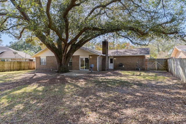 rear view of house featuring a gate, fence, a chimney, a patio area, and brick siding