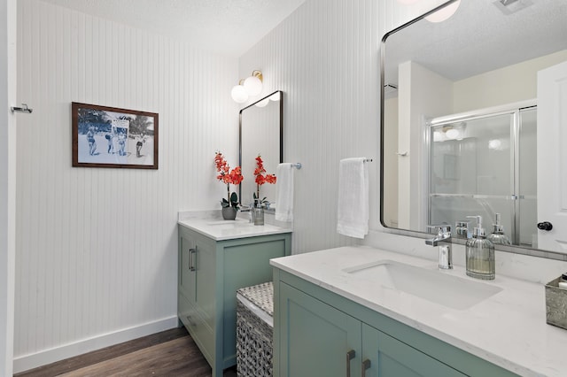 2381 W County Highway 30a Unit 8, Santa Rosa Beach, FL 32459 - bathroom with wood finished floors, a shower stall, two vanities, and a textured ceiling